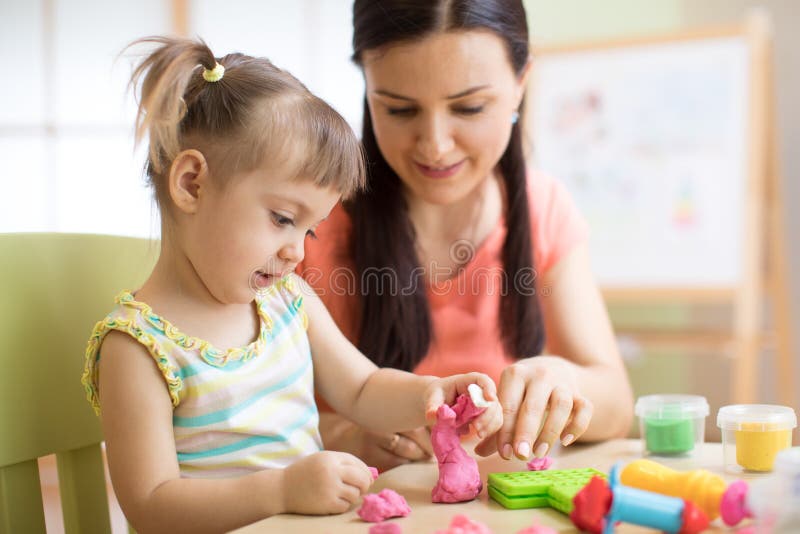 Mother and kid daughter at home molded from clay and play together. Concept of preschool or home education.