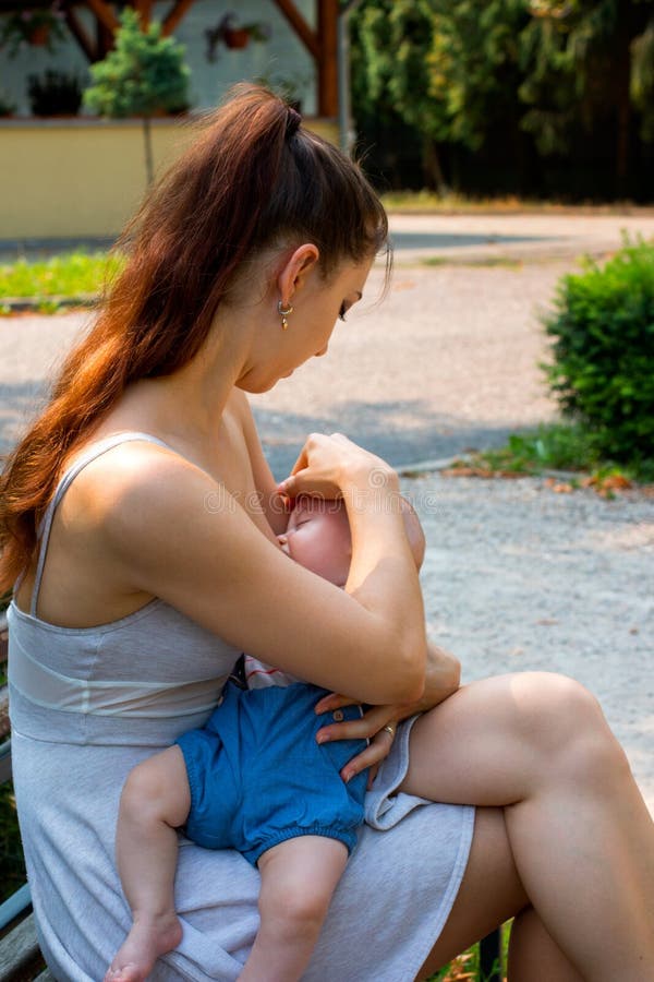 Young mom breastfeeding her cute hungry baby in public on sunny day royalty free stock photo Young mom breastfeeding her cute hungry baby in public on sunny day royalty free stock photo
