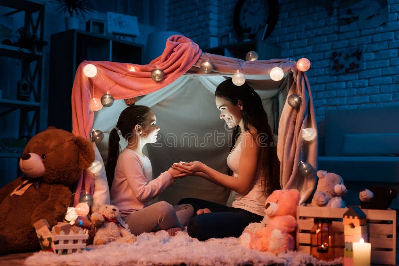 Mother and daughter holding flashlight their hands in pillow house late at night at home. royalty free stock images Mother and daughter holding flashlight their hands in pillow house late at night at home. royalty free stock images