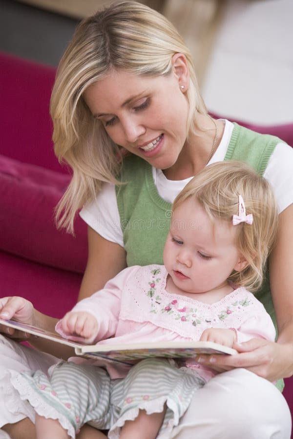 Mother in living room reading book with baby stock photos