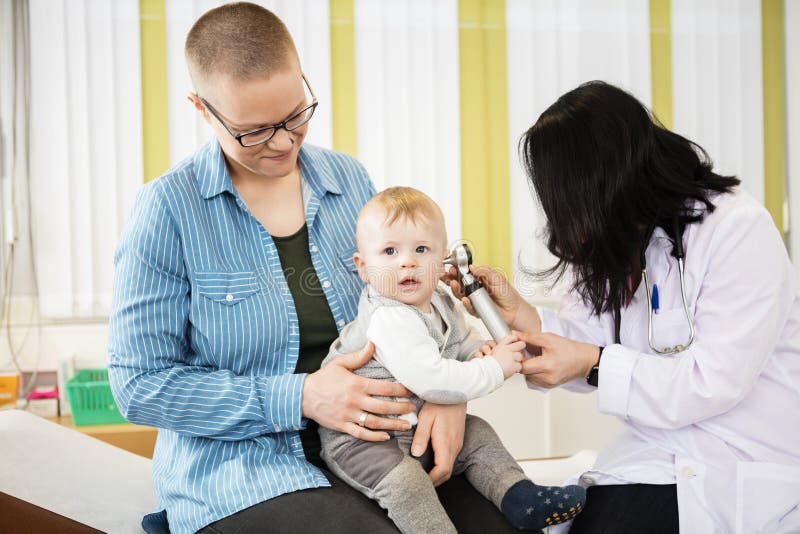 Mother Looking At Baby Being Examined By Female Doctor stock image Mother Looking At Baby Being Examined By Female Doctor stock image