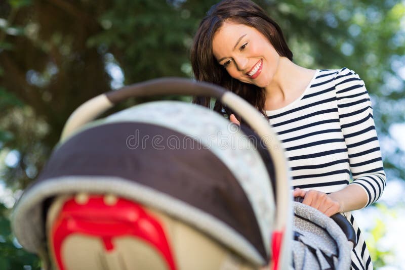 Mother Looking Into Baby Carriage In Park stock photography Mother Looking Into Baby Carriage In Park stock photography