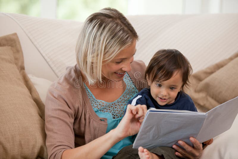 Mother looking at a book with her son stock photos