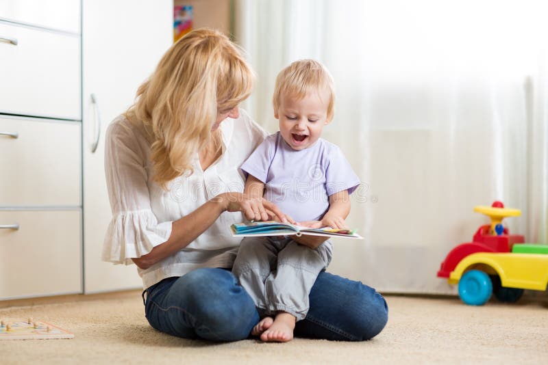 Mother looking at a book with her son at home stock photography