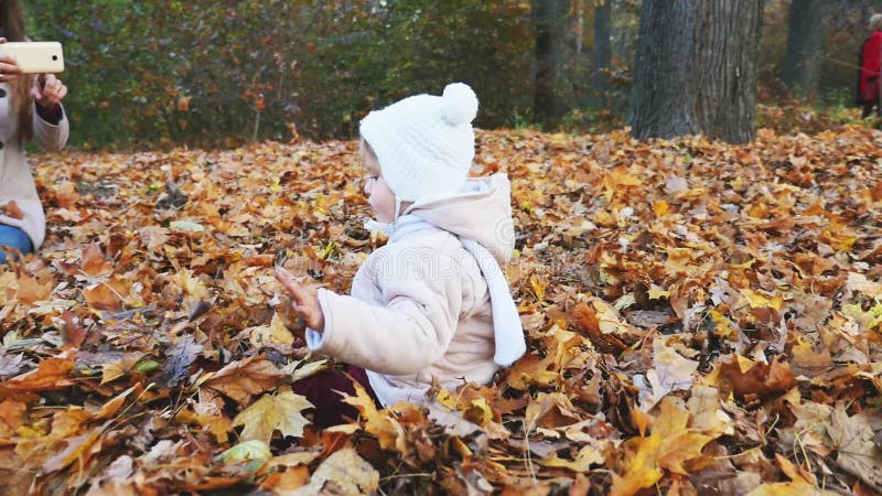 Mother makes footage of baby at autumn park, mobile phone
