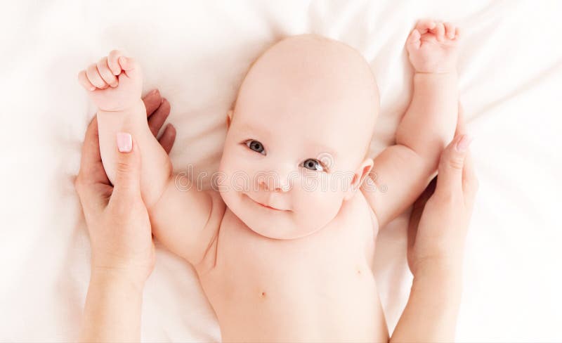 Mother massaging the belly of her four month old baby in bed at home, top view. Top smiling cheerful stock images, royalty-free photos and pictures