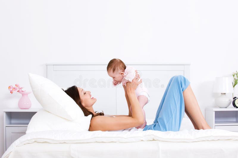 Mother playing with baby on the bed
