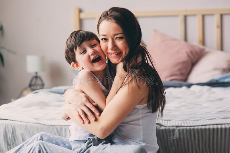 Mother playing with child son in bedroom. Happy family wearing pajamas stock photo Mother playing with child son in bedroom. Happy family wearing pajamas stock photo