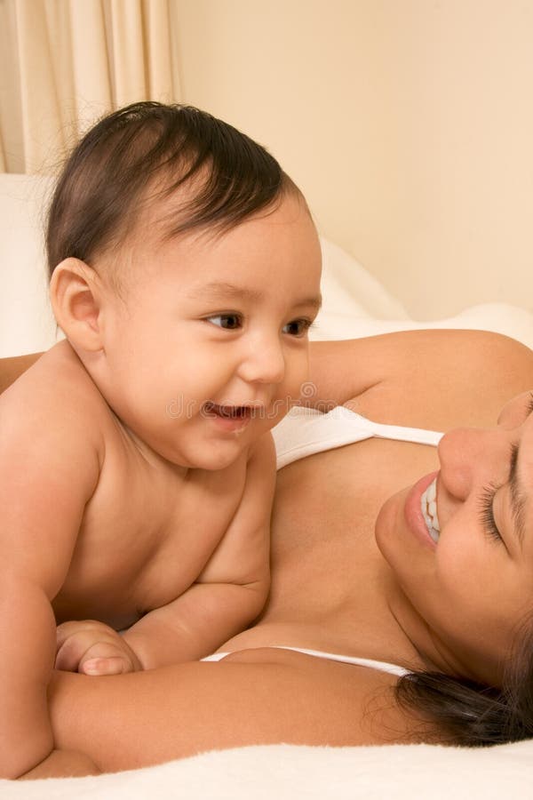Om and son on bed and mother embracing the infant baby playing with him. Happy multiethnic boys stock images, royalty-free photos and pictures
