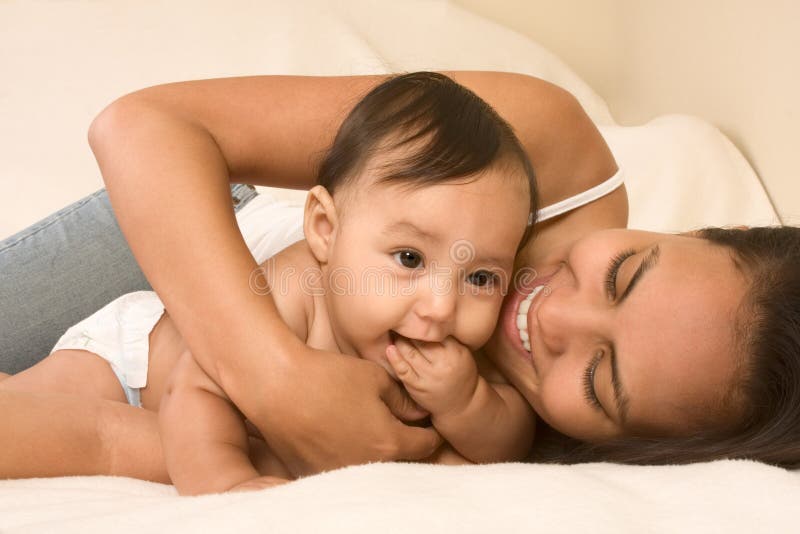 Mother playing with her baby boy son on bed stock photo