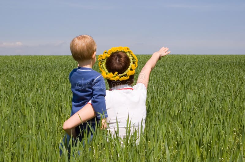 Mother point the way to her little son against green meadow. Mother point the way to her little son against green meadow