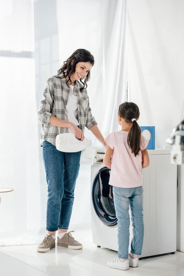 mother pouring liquid laundry detergent in washer wile daughter in pink t-shirt standing near stock photography mother pouring liquid laundry detergent in washer wile daughter in pink t-shirt standing near stock photography