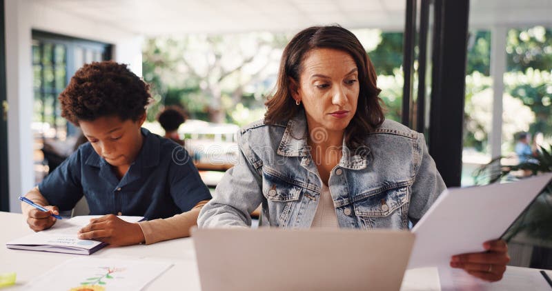 Mother, remote work and boy with education, multitasking and documents with laptop at apartment. People, mom and child stock photo