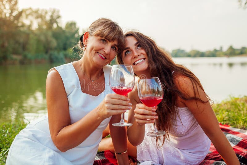 Mother`s day. Mother drinking wine with her adult daughter in spring park. Family having picnic outdoors