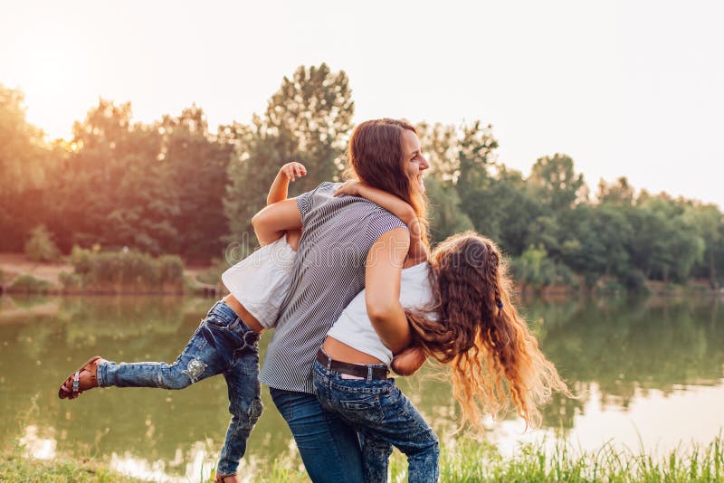 Mother`s day. Family playing and having fun by summer river. Mother holding and spinning daughters stock photography Mother`s day. Family playing and having fun by summer river. Mother holding and spinning daughters stock photography