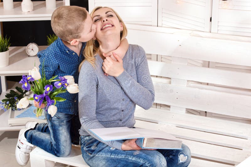 Son congratulates his beloved mother and gives her a bouquet of tulips.The concept of the celebration,woman`s day.Mother`s Day. stock photography Son congratulates his beloved mother and gives her a bouquet of tulips.The concept of the celebration,woman`s day.Mother`s Day. stock photography