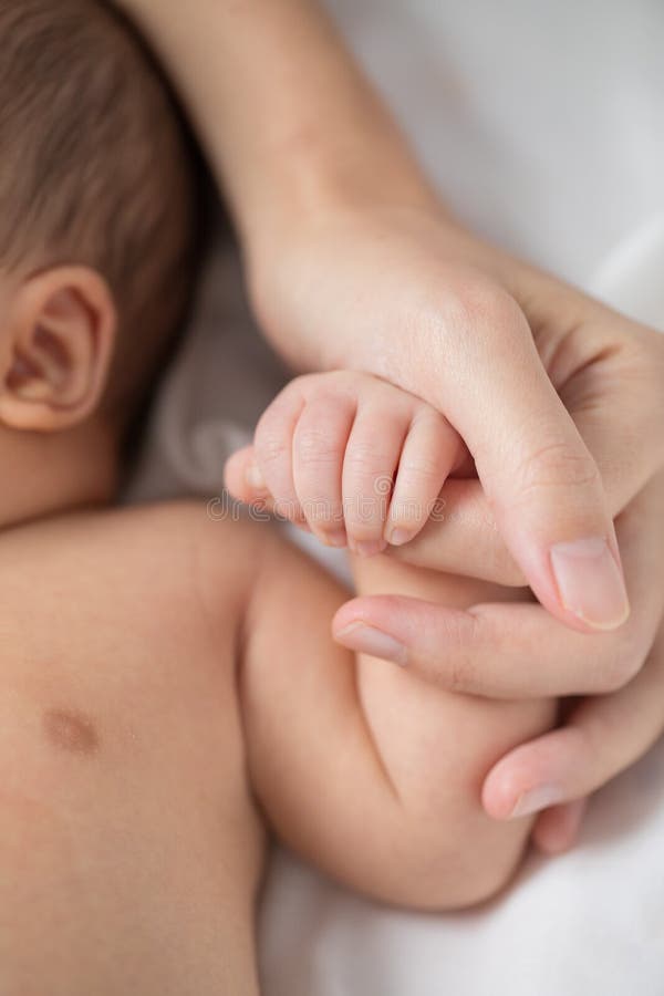 Mother`s hand holding infant baby boy`s hand with tender love and care. Mother`s hand holding infant baby boy`s hand with tender love and care.