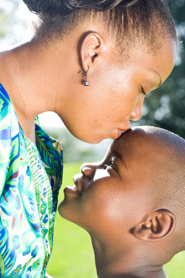 Happy african mother kissing son showing her love to the kid stock photogra...