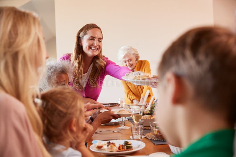 Mother Serving Food As Multi-Generation Family Meet For Meal At Home royalty free stock photography