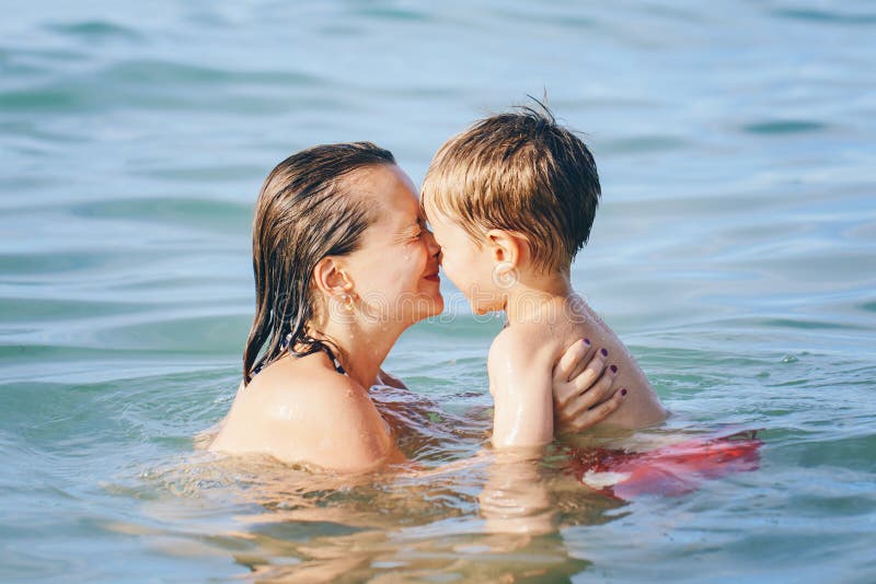 Mother and son child boy playing hugging in water diving in sea ocean