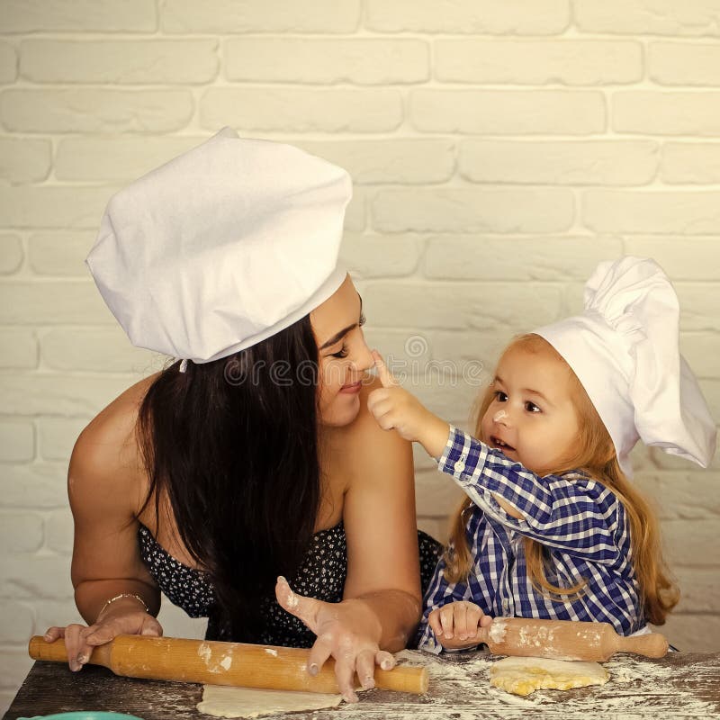 Mother and son cook together. Kid painting with flour on girl nose.