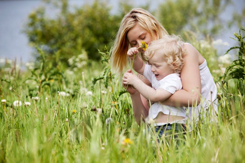 A mother and son having fun playing with flowers in a grass field. A mother and son having fun playing with flowers in a grass field