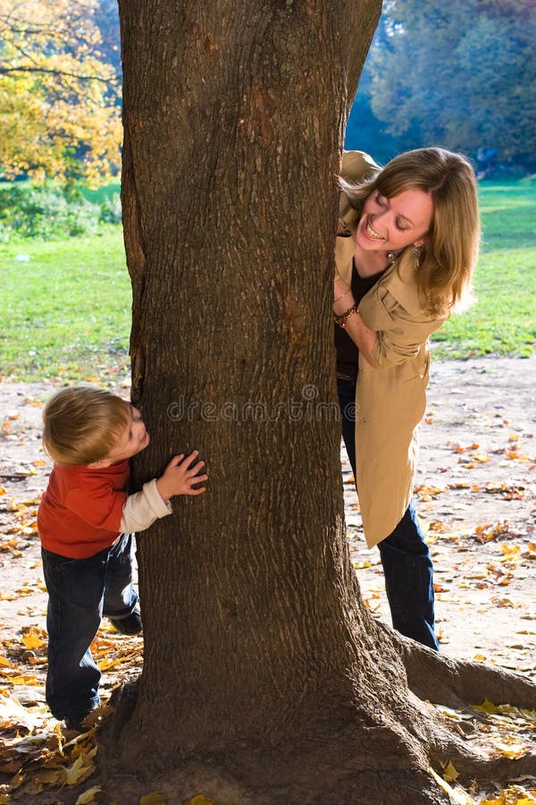 Madre e figlio giocare a nascondino in autunno parco.