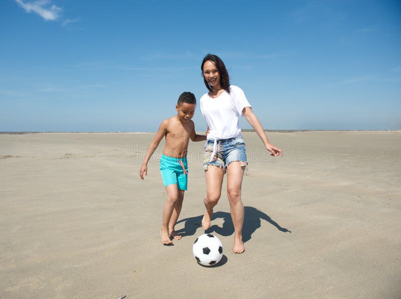 Mother and son playing football on the beach