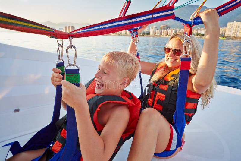 Mother and son sit in motorboat and ready to paraglide