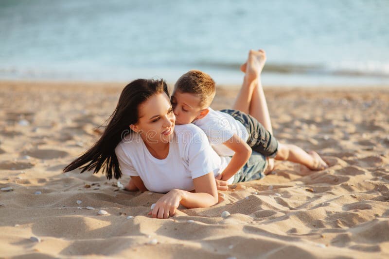 Mother and son sitting on the beach stock photos.