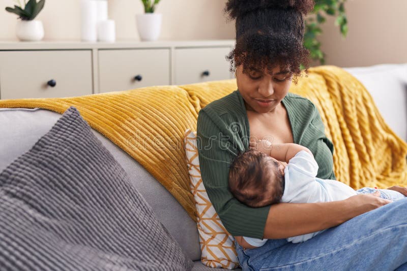 Mother and son sitting on sofa breastfeeding at home