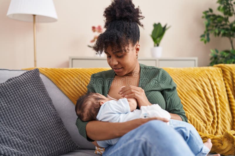 Mother and son sitting on sofa breastfeeding at home