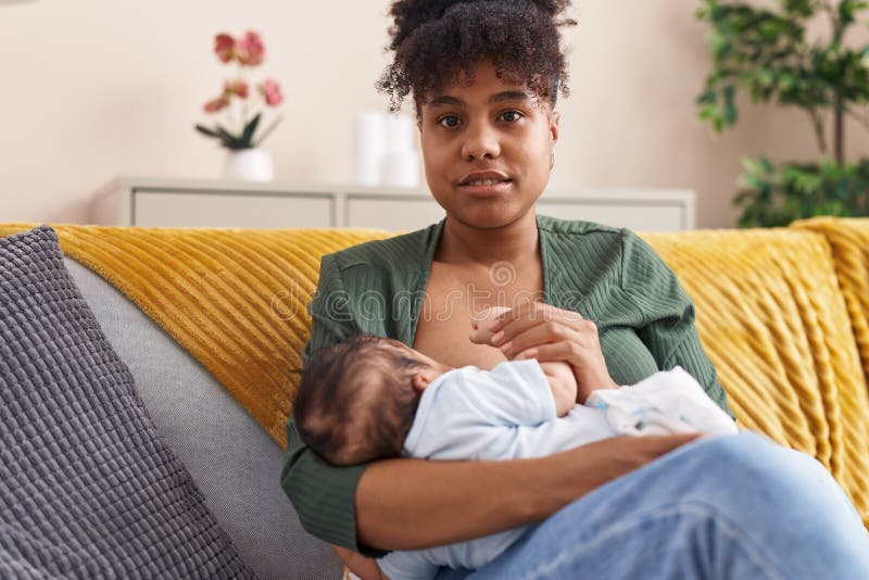 Mother and son sitting on sofa breastfeeding at home