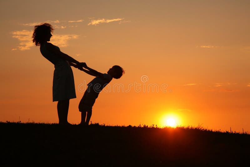 Mother and son on sunset holding by hands