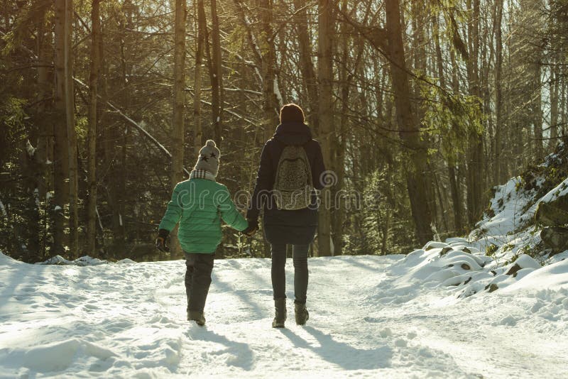 Mother with son walking along snow-covered road against the background of coniferous forest. Winter sunny day royalty free stock image Mother with son walking along snow-covered road against the background of coniferous forest. Winter sunny day royalty free stock image