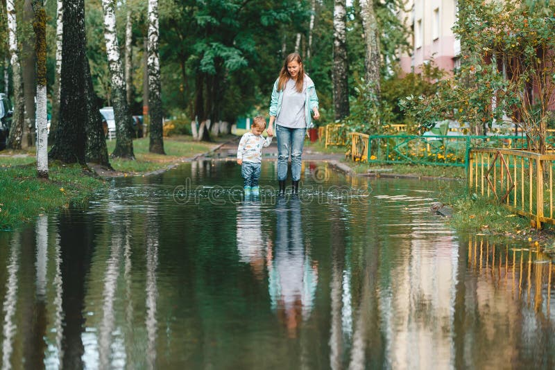 Mother and son walking in the fresh air in rubber boots on the puddles after the rain on summer day royalty free stock photo Mother and son walking in the fresh air in rubber boots on the puddles after the rain on summer day royalty free stock photo
