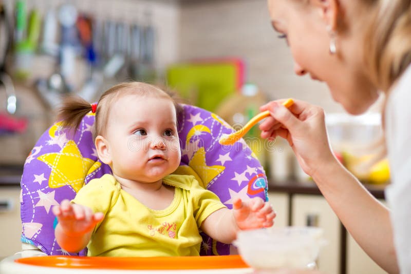 Mother spoon feeding child toddler