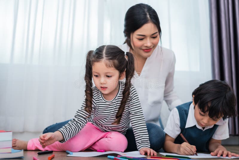 Mother teaching children in drawing class. Daughter and son painting with colorful crayon color in home. Teacher training students in art classroom. Education and Learning development of kids theme