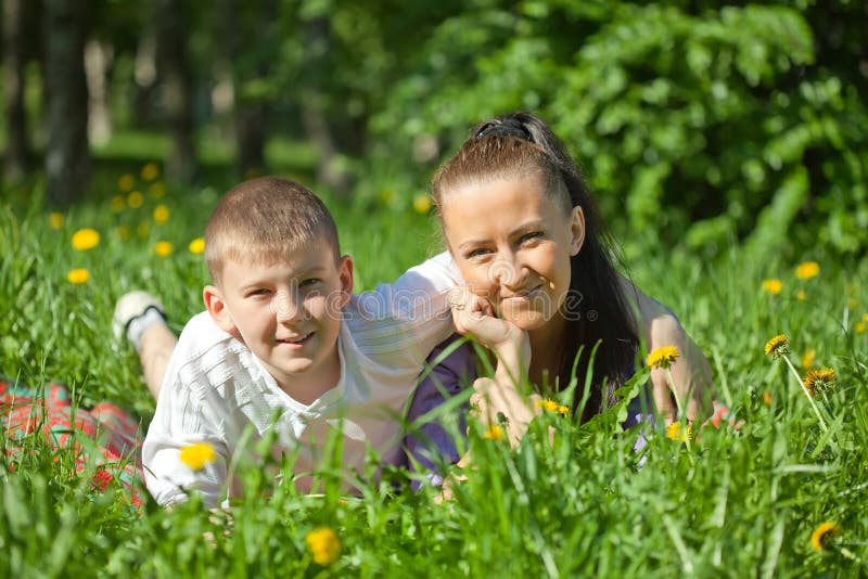 Mother and teenager son laying on the green grass