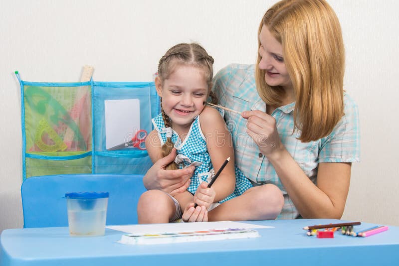 Mother tickles her five-year daughter brush for drawing