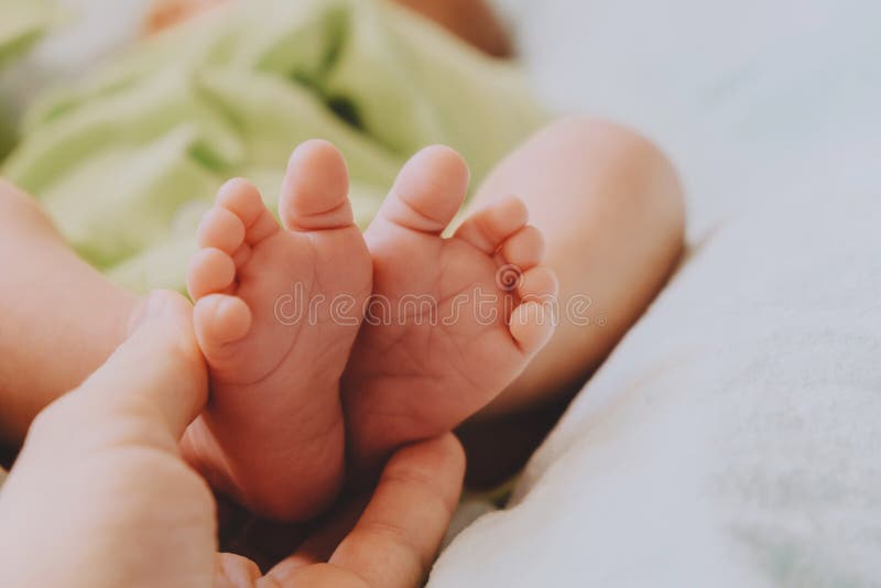 Maternity concept. Mom`s hand touching cute little newborn baby feet. stock photos