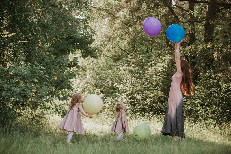 Mother and two daughters holding hands circling. Family time together. Funny time. Girls with balloons. Soft focus stock image Mother and two daughters holding hands circling. Family time together. Funny time. Girls with balloons. Soft focus stock image