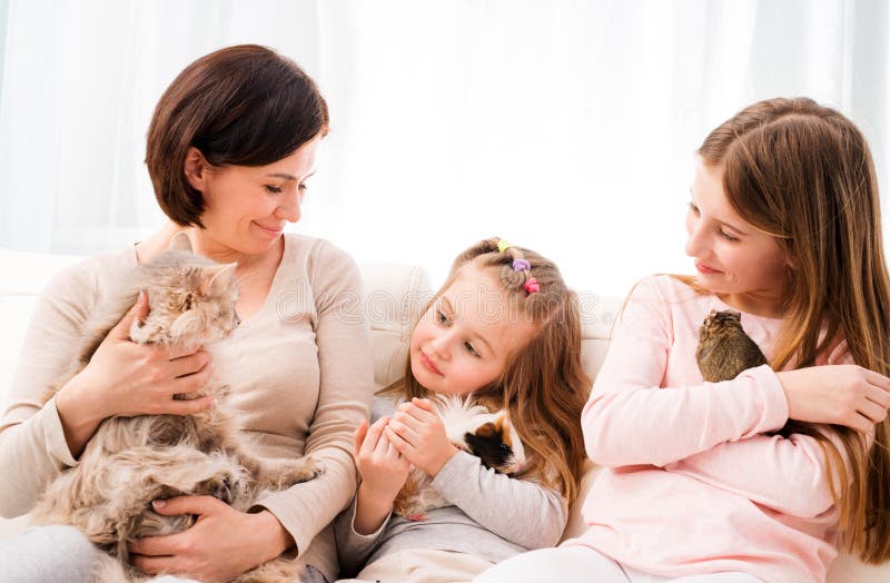 Mother and two daughters holding their favorite pets on hands.