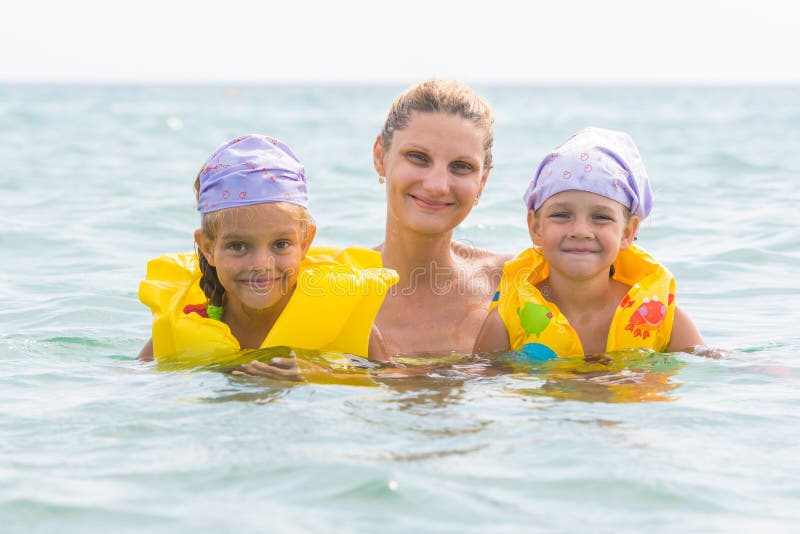 Mother and two daughters swimming in sea stock photos Mother and two daughters swimming in sea stock photos