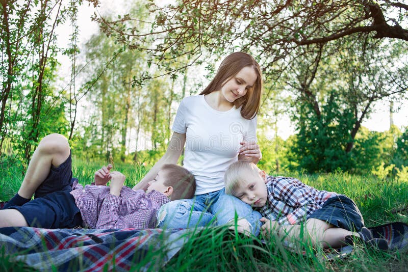 Mother and two sons on the nature. Picnic with family at the Park. Calm children.