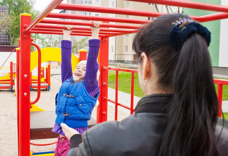 Mother watching play on the playground daughter