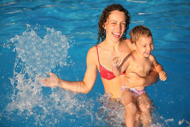 Mother in water with child makes heart with drops