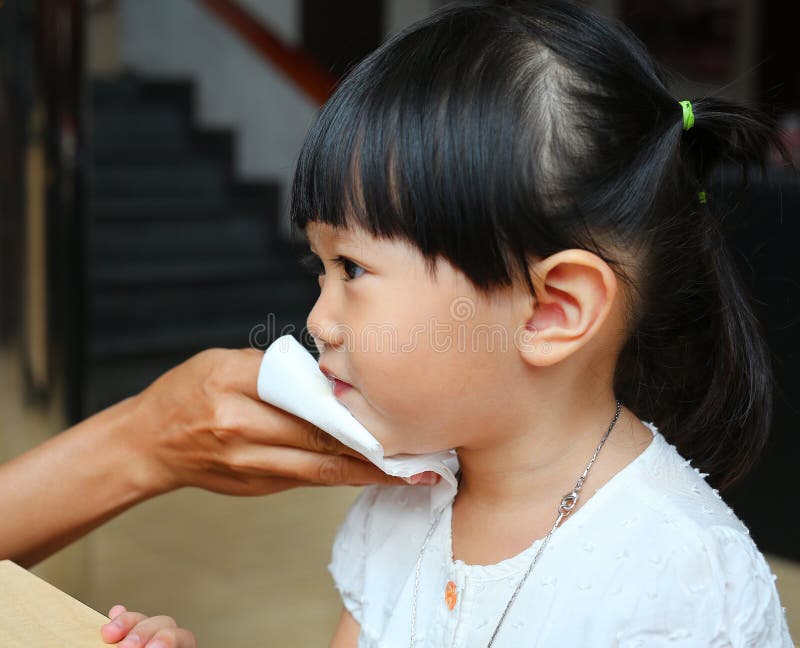 Mother wipes baby`s mouth with tissue paper