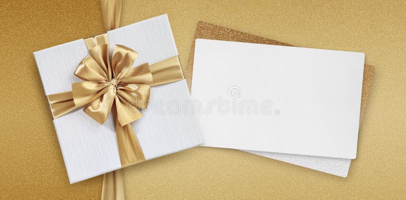 Mothers day gift card, box with golden ribbon bow and white ticket for copy space isolated on beige glittering background, top