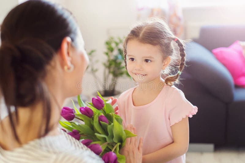 Mothers day, little girl giving flowers to her mum